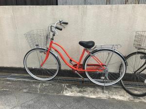 een rode fiets geparkeerd naast een muur bij Melody Heim 2C in Tokushima