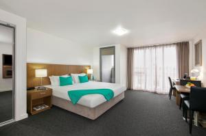a hotel room with a large bed and a desk at Quest Cheltenham in Cheltenham