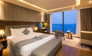 a bedroom with a bed and a desk and a large window at DTX Hotel Nha Trang in Nha Trang