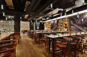 a restaurant with wooden tables and chairs and a brick wall at Andaz 5th Avenue, By Hyatt in New York