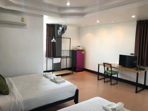 a room with two beds and a desk and a tv at Khaohom House in Chiang Mai