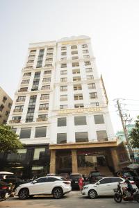 a white building with cars parked in front of it at Khách sạn Hoàng Thái in Sầm Sơn