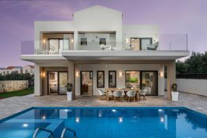a villa with a swimming pool in front of a house at Villa Kambos Platanias in Plataniás