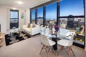 ein Wohnzimmer mit einem Glastisch und weißen Stühlen in der Unterkunft Winston Apartments in Melbourne