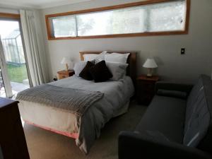 1 dormitorio con cama, sofá y ventana en Whaka Heights en Christchurch