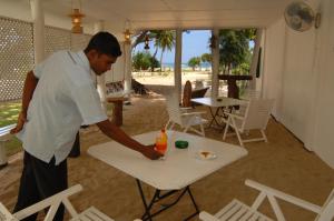 Um homem ao lado de uma mesa com uma bebida. em Pigeon Island Beach Resort em Nilaveli