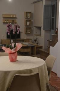 Kalymnos Suite home في كاليمنوس: طاولة مع مزهرية مع الزهور الأرجوانية عليها