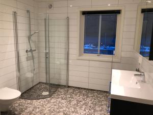 a bathroom with a shower and a toilet and a window at Balestrand Fjordapartments in Balestrand