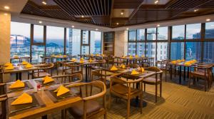 un restaurant avec des tables et des chaises et de grandes fenêtres dans l'établissement DTX Hotel Nha Trang, à Nha Trang