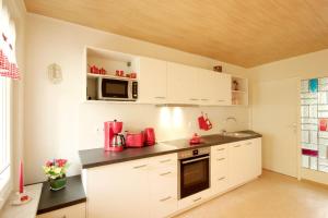 Una cocina con gabinetes blancos y electrodomésticos rojos. en Bungalow am Schmachter See by Rujana, en Binz 3 fotos más