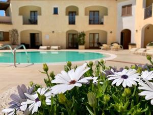a pool with white flowers in front of a building at Hotel Monti Di Mola in Porto Cervo