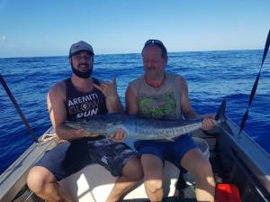 two men sitting in a boat holding a fish at AU FARE MOENAU in Paea