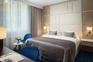 a hotel room with a large bed and blue chairs at Hotel KINGS COURT in Prague