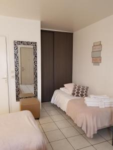 a bedroom with two beds and a mirror in it at Hôtel L'ideal le Mountbatten in Arromanches-les-Bains