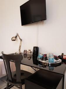 a desk with a chair and a television on a wall at Hôtel L'ideal le Mountbatten in Arromanches-les-Bains