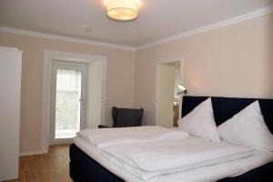 a bedroom with a white bed with a chair and a window at Apartment Torhaus Schloss Wocklum in Balve