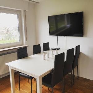 a white table with chairs and a flat screen tv on a wall at Ferien in Neuffen - Ferienwohnung Plaue in Neuffen