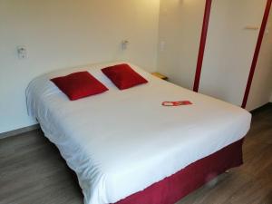 1 cama blanca grande con almohadas rojas en una habitación en Fasthotel, en Jaux