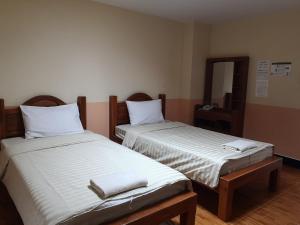 two beds sitting next to each other in a room at Sab Suwarn Mansion in Suphan Buri