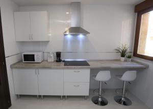 薩拉曼卡的住宿－Apartamento turisticos Puente Romano P3 2-A，厨房配有白色橱柜和带凳子的台面
