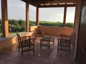 a porch with chairs and a table and a window at The Bell Tower Lodge in Palidoro