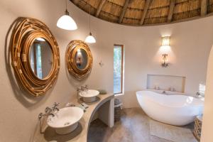 a bathroom with two sinks and a tub and mirrors at Nyala Safari Lodge in Hoedspruit +56 photos