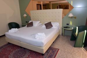 a bedroom with a bed with two chairs and a mirror at Hotel Diamante in Corbetta