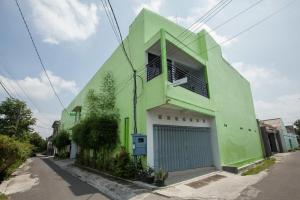 una casa verde con un garaje en una calle en RedDoorz @ Kartohardjo Madiun, en Madiun