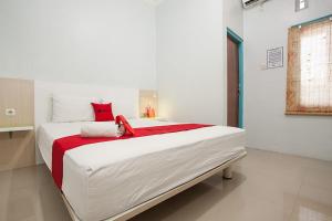 a bedroom with a large white bed with red accents at RedDoorz @ Kartohardjo Madiun in Madiun