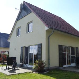 a house with a pitched roof with a table and chairs at Ferienhaus Buche im Land Fleesensee in Göhren-Lebbin