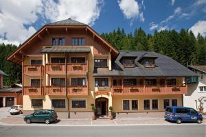 un grand bâtiment avec des voitures garées devant lui dans l'établissement Sporthotel Dachstein West, à Annaberg-Lungötz