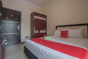 a bedroom with a large white bed with red pillows at RedDoorz near E Walk Mall Balikpapan in Balikpapan