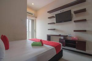 um quarto com uma cama e uma televisão de ecrã plano na parede em RedDoorz near E Walk Mall Balikpapan em Balikpapan