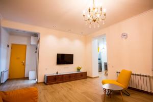 a living room with a couch and a tv on the wall at Yellow apartment in Avlabari in Tbilisi City