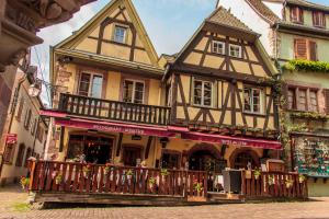 a building with a balcony in front of it at Hotel Au Cerf in Riquewihr