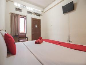 RedDoorz @ Buah Batu 3 في باندونغ: غرفة نوم بسرير ابيض كبير مع بطانيه حمراء