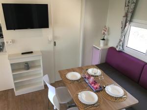 ein Esszimmer mit einem Tisch und einem lila Sofa in der Unterkunft CHERRY Premium ADRIA Mobile homes Zelena Laguna in Poreč