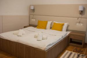 a large bed with white sheets and yellow pillows at Villa Eva in Gradac