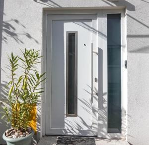 une porte blanche sur une maison blanche avec deux plantes dans l'établissement Apartman Zagreb Maksimir, à Zagreb