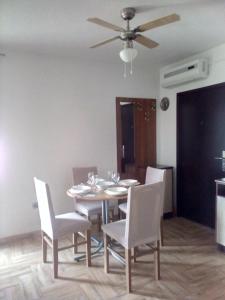 a dining room table with white chairs and a ceiling fan at Apartman Edi in Nin