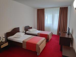una camera d'albergo con 2 letti e una scrivania di Hostel Caliman a Caciulata