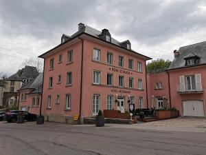 un gran edificio rosa en una calle de la ciudad en Hotel-Restaurant Beim Schlass, en Wiltz