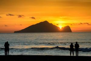 a group of people standing on the beach watching the sunset at Vanilla Twilight in Wujie
