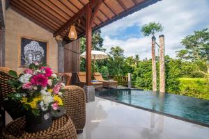 a villa with a swimming pool and a patio at Alam Dania Cottage in Ubud