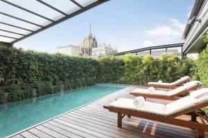 a swimming pool with two lounge chairs on a deck at Sina De La Ville in Milan