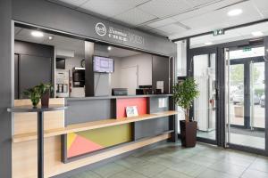 un vestíbulo de una oficina con escritorio y algunas plantas en B&B HOTEL Lyon Vénissieux, en Vénissieux