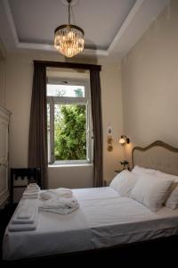 sypialnia z łóżkiem z żyrandolem i oknem w obiekcie Kyria Boutique House w Atenach