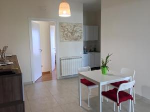 una cucina e una sala da pranzo con tavolo e sedie bianchi di B&B Riccio&Lella a Fiumicino