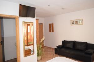 a living room with a black couch and a tv at Landgasthof Am Teufelstisch in Hinterweidenthal