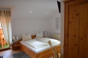 um quarto com uma cama com lençóis brancos e uma janela em Landgasthof Am Teufelstisch em Hinterweidenthal
